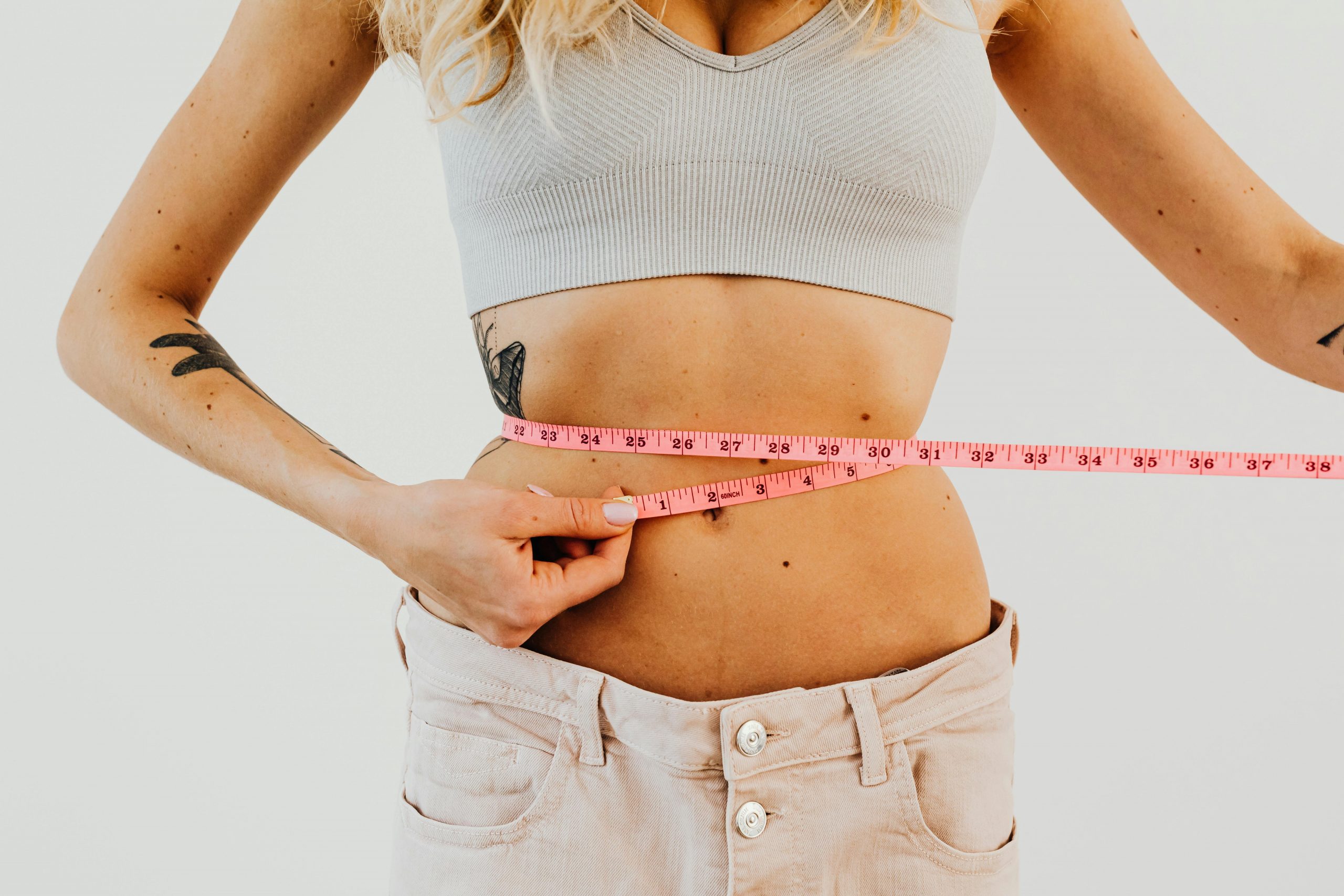 woman measuring her waistline with a tape measure
